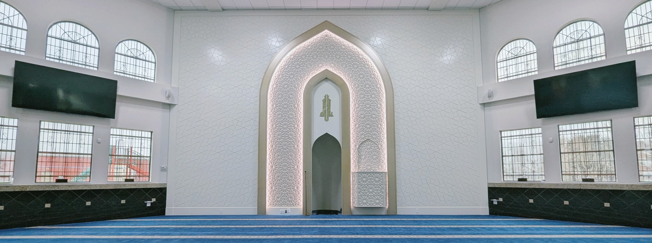 Masjid Hamza prayer hall mihrab and blue carpet in Houston, Texas