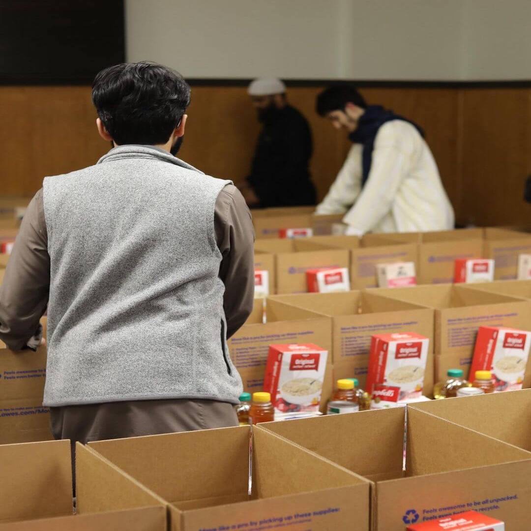 Masjed Assaber community service volunteers preparing food boxes indoors