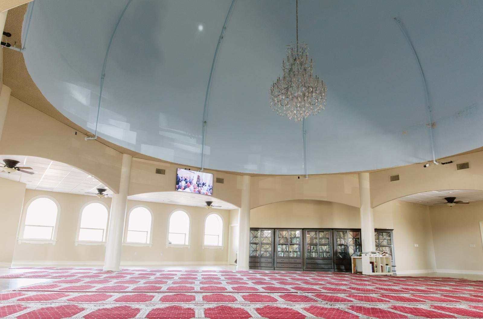 Prayer hall inside Masjid Fresno Islamic Center with red prayer carpet and dome ceiling